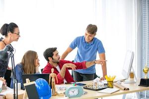 grupo diverso de jóvenes empresarios discutiendo un proyecto de trabajo mientras se sientan juntos en una mesa en una oficina moderna. concepto de coworking foto