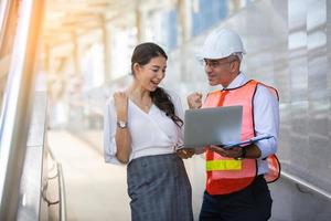 el ingeniero y la mujer de negocios revisando el portapapeles en el edificio del sitio de construcción. el concepto de ingeniería, construcción, vida urbana y futuro. foto