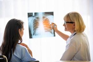 Female doctor show image of xray film to female patient and explain to her. photo