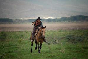 Cowboy on horseback against a beautiful sunset, cowboy and horse at first light, mountain, river and lifestyle with natural light background photo