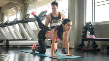 Couple Athlete sporty people doing exercise with abs roller wheel to strengthen their abdominal muscle in gym. photo