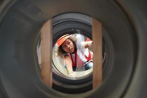 Female industrial engineer wearing a safety helmet while standing in a heavy industrial factory. The Maintenance looking of working at industrial machinery and check security system setup in factory. photo