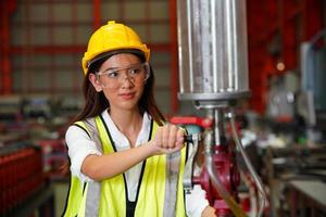 mujer ingeniera industrial que usa un casco de seguridad mientras está de pie en una fábrica industrial pesada. el mantenimiento que busca trabajar en maquinaria industrial y verificar la configuración del sistema de seguridad en fábrica. foto