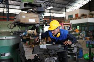 Professional industrial factory employee working with machine part, checking and testing industrial equipment and robot arms in large Electric electronics wire and cable manufacturing plant factory