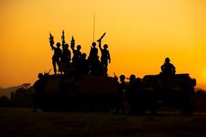 Silhouettes of army soldiers in the fog against a sunset, marines team in action, surrounded fire and smoke, shooting with assault rifle and machine gun, attacking enemy photo