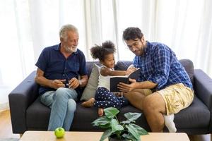 Diverse friendly family sits on the comfortable couch in cozy living room, a multiracial parents and their children enjoy time together at home photo