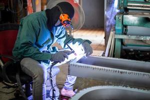 Welder used grinding stone on steel in factory with sparks, Welding process at the industrial workshop, hands with instrument in frame. photo