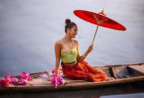 jóvenes asiáticas con vestimenta tradicional en el bote y flores de loto rosa en el estanque.hermosas chicas con traje tradicional.chica tailandesa con vestido retro tailandés, chica tailandesa con traje tradicional foto