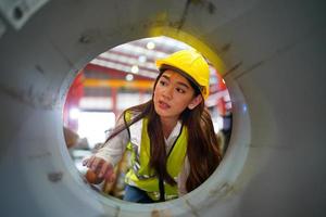 la capataz de la trabajadora o el trabajo del trabajador en el sitio de la fábrica revisan la máquina o los productos en el sitio. ingeniero o técnico revisando material o máquina en planta. industrial y fábrica. foto