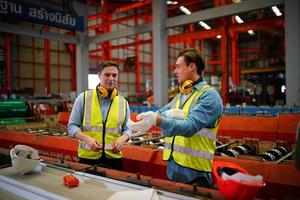 el capataz de los trabajadores de la industria o el trabajo de los trabajadores en el sitio de la fábrica revisan la máquina o los productos en el sitio. ingeniero o técnico revisando material o máquina en planta. industrial y fábrica. foto