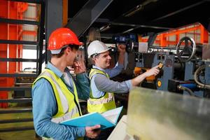 ingeniero industrial masculino con casco de seguridad mientras está de pie en una fábrica industrial pesada. el mantenimiento que busca trabajar en maquinaria industrial y verificar la configuración del sistema de seguridad en fábrica. foto