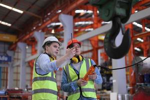 el capataz de los trabajadores de la industria o el trabajo de los trabajadores en el sitio de la fábrica revisan la máquina o los productos en el sitio. ingeniero o técnico revisando material o máquina en planta. industrial y fábrica. foto