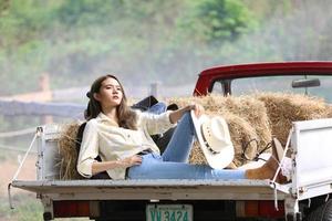 Cowgirl model posing on farm. A portrait of a beautiful young cowgirl leaning against a wall in a stable at farm. photo