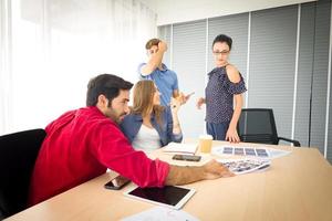 grupo diverso de jóvenes empresarios discutiendo un proyecto de trabajo mientras se sientan juntos en una mesa en una oficina moderna. concepto de coworking foto