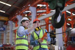 el capataz de los trabajadores de la industria o el trabajo de los trabajadores en el sitio de la fábrica revisan la máquina o los productos en el sitio. ingeniero o técnico revisando material o máquina en planta. industrial y fábrica. foto