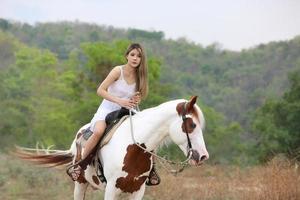 mujer joven con su caballo en la luz del atardecer. fotografía al aire libre con una modelo de moda. estado de ánimo de estilo de vida foto