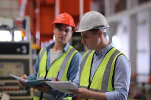 Men industrial engineer wearing a safety helmet while standing in a heavy industrial factory. The Maintenance looking of working at industrial machinery and check security system setup in factory. photo