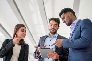 Multiethnic business people working together and discussing over tablet. photo