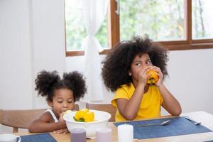 feliz familia multinacional de raza mixta con hijas que preparan ensalada fresca orgánica vegetal, disfrutan del proceso de cocina de pasatiempos en una cocina acogedora, alimentación saludable, los padres enseñan a los niños, actividades de fin de semana en casa foto