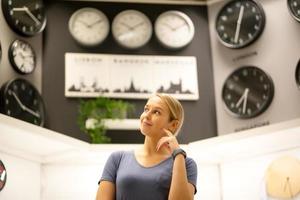 portrait of women looking away while standing against clocks on wall photo