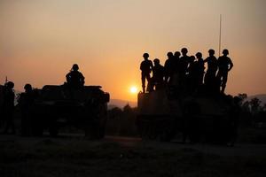 Silhouettes of army soldiers in the fog against a sunset, marines team in action, surrounded fire and smoke, shooting with assault rifle and machine gun, attacking enemy photo