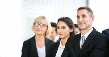 Successful business people standing together widen out showing strong relationship of worker community. A team of businessman and businesswoman expressing a strong group teamwork at the modern office. photo