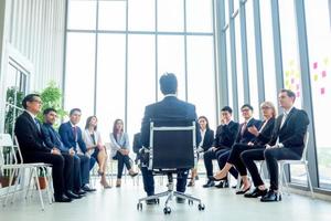 Group of people listening to experienced business professional helping them work out new corporate strategy. photo