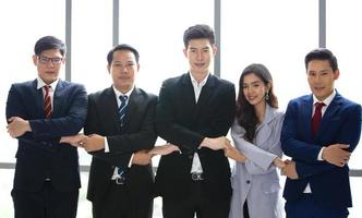 Successful business people standing together widen out showing strong relationship of worker community. A team of businessman and businesswoman expressing a strong group teamwork at the modern office. photo