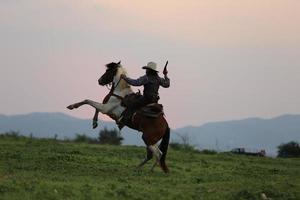vaquero a caballo contra una hermosa puesta de sol, vaquero y caballo a primera luz, montaña, río y estilo de vida con fondo de luz natural foto