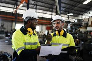 Maintenance Engineers is working in front of the automated CNC machinery repair on a maintenance checklist at the production line. photo