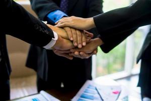 business team working at trendy loft office. Young mixed race group of people puts palm together on the centre. Teamwork of happy guys, colleagues. photo