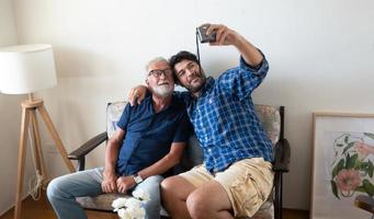 A portrait of adult hipster son and senior father spend time together on weekend at home. photo