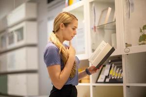 side view of women looking for something on bookshelf photo