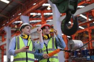 el capataz de los trabajadores de la industria o el trabajo de los trabajadores en el sitio de la fábrica revisan la máquina o los productos en el sitio. ingeniero o técnico revisando material o máquina en planta. industrial y fábrica. foto