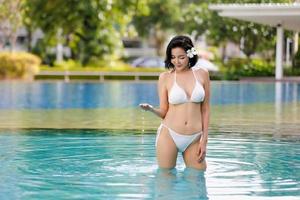 Young woman enjoying a sun, Slim young girl model in white bikini  by the pool. photo