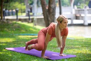 hermosa rubia activa haciendo ejercicio de yoga y entrenamiento al aire libre.