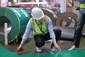 Men industrial engineer wearing a safety helmet while standing in a heavy industrial factory. The Maintenance looking of working at industrial machinery and check security system setup in factory. photo