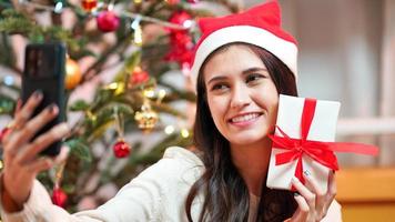 Woman s hands wrapping Christmas gift boxes, close up. Cropped female sit and preparing natural eco presents on couch with decor elements and items. Merry Christmas or New year DIY packing Concept. photo