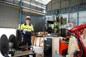 Professional industrial factory employee working with machine part, checking and testing industrial equipment and robot arms in large Electric electronics wire and cable manufacturing plant factory photo