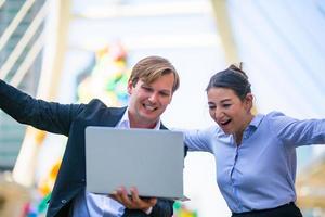 hombre de negocios que muestra contenido en tableta a una colega. hombre y mujer de negocios caminando afuera, usando tableta, hablando, sonriendo, riendo. concepto de comunicación foto