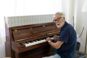 Retired elderly man with gray hair are playing piano on daytime for relaxing photo