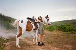 mujer joven con su caballo en la luz del atardecer. fotografía al aire libre con una modelo de moda. estado de ánimo de estilo de vida foto