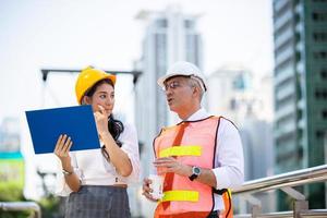 el ingeniero y la mujer de negocios revisando el portapapeles en el edificio del sitio de construcción. el concepto de ingeniería, construcción, vida urbana y futuro. foto