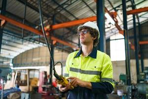 Industrial engineer or worker wearing a helmet while standing in a heavy industrial factory. The Maintenance looking of working at industrial machinery and check security system setup in factory. photo