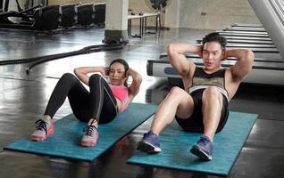 pareja atleta deportistas haciendo ejercicio con rueda de rodillos abs para fortalecer su músculo abdominal en el gimnasio. foto