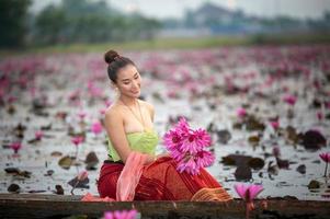 jóvenes asiáticas con vestimenta tradicional en el bote y flores de loto rosa en el estanque.hermosas chicas con traje tradicional.chica tailandesa con vestido retro tailandés, chica tailandesa con traje tradicional foto