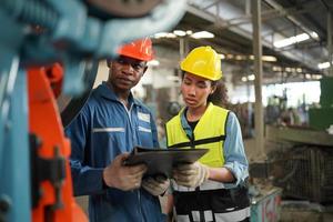 los ingenieros de mantenimiento están trabajando frente a la reparación automatizada de maquinaria cnc en una lista de verificación de mantenimiento en la línea de producción. foto