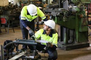 los ingenieros de mantenimiento están trabajando frente a la reparación automatizada de maquinaria cnc en una lista de verificación de mantenimiento en la línea de producción. foto