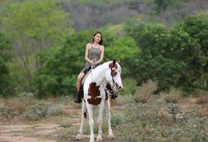 mujer joven con su caballo en la luz del atardecer. fotografía al aire libre con una modelo de moda. estado de ánimo de estilo de vida foto