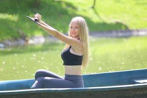 A beautiful woman in gym clothes is sitting in a boat and enjoying the nature in the garden during the day. photo